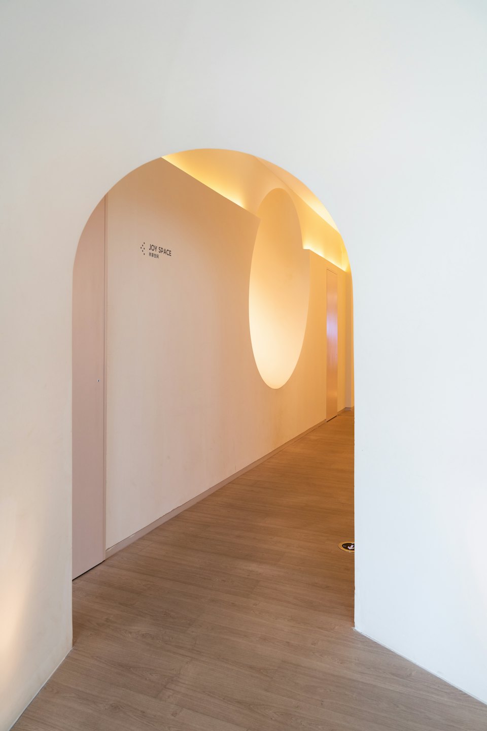 Modern hallway with arched doorways and wood-look flooring.